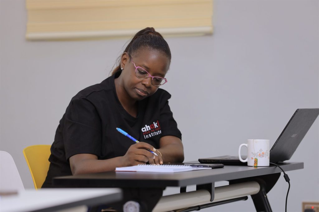 AIHS student taking notes with a laptop on campus